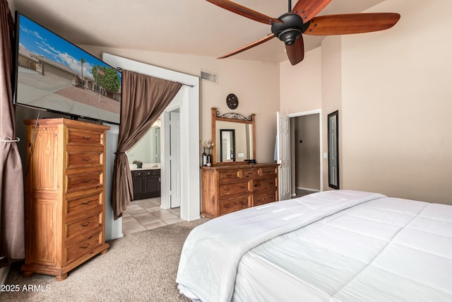 bedroom featuring visible vents, a ceiling fan, ensuite bathroom, light colored carpet, and vaulted ceiling