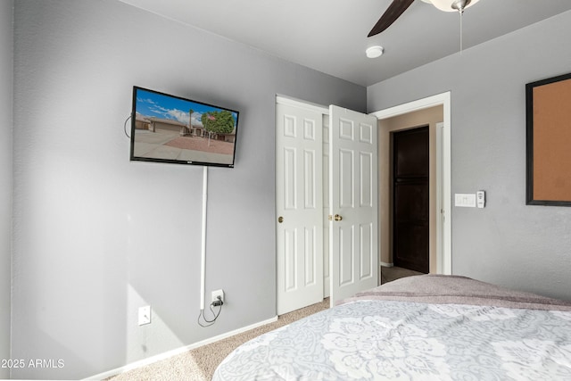 bedroom with a closet, baseboards, a ceiling fan, and carpet