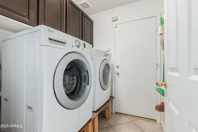 clothes washing area featuring light tile patterned floors, visible vents, cabinet space, and washer and clothes dryer