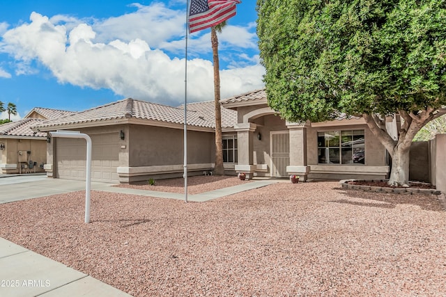 view of front of home featuring a tile roof, a garage, driveway, and stucco siding