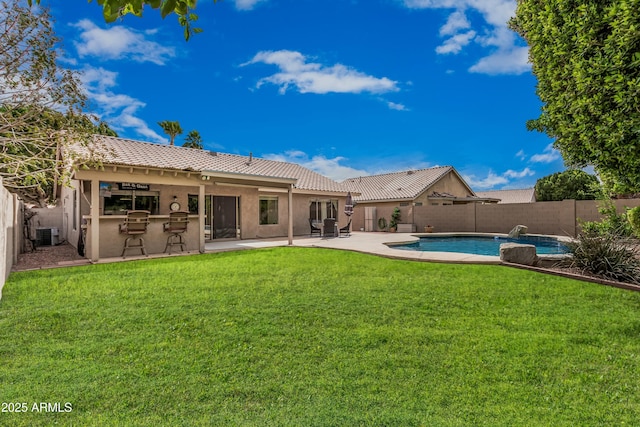 back of property featuring a yard, a fenced backyard, and a tiled roof