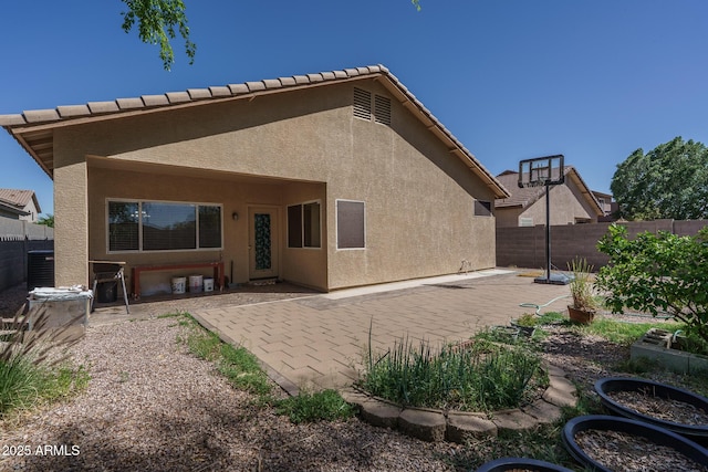 back of house with stucco siding, a fenced backyard, and a patio