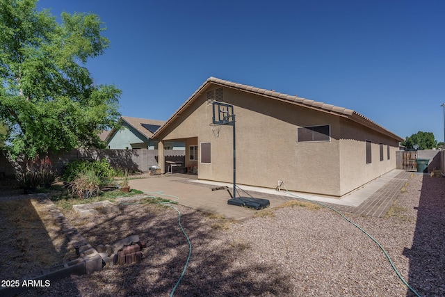rear view of house featuring a patio, a fenced backyard, and stucco siding