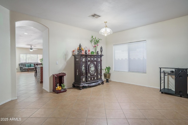 sitting room featuring tile patterned floors, visible vents, arched walkways, and baseboards