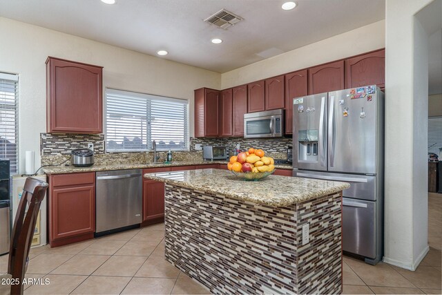 kitchen featuring light tile patterned flooring, a sink, light stone countertops, stainless steel appliances, and visible vents