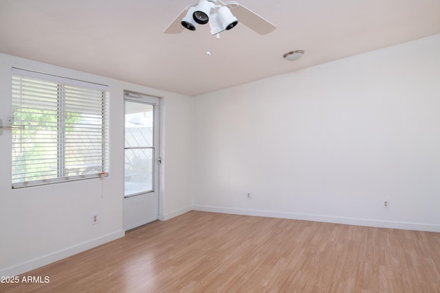 spare room with ceiling fan, light wood-type flooring, and baseboards