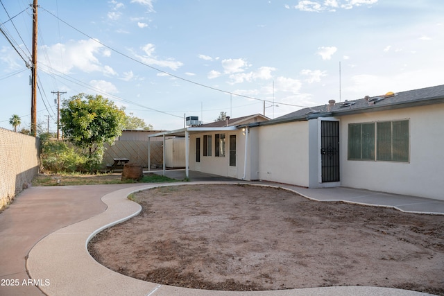 rear view of property featuring stucco siding, a fenced backyard, and a patio area