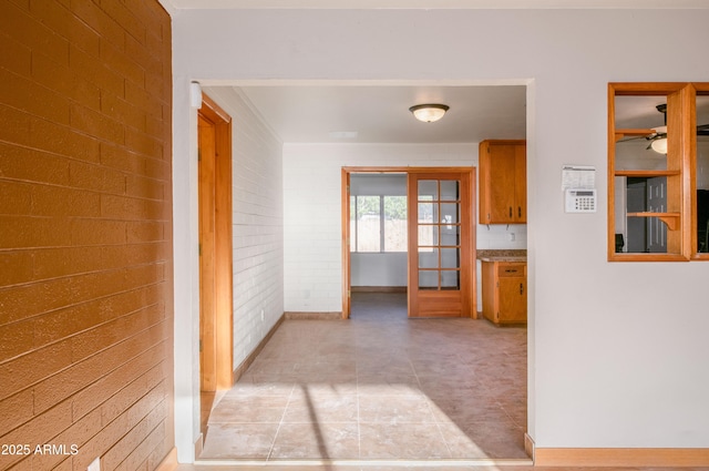 corridor featuring light tile patterned floors, french doors, and brick wall