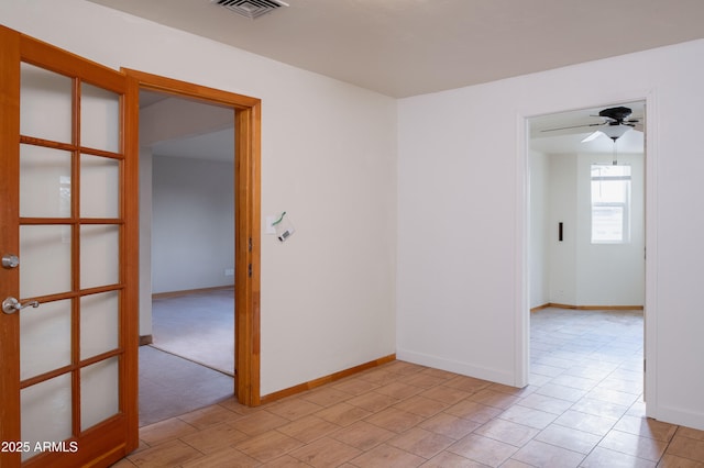 empty room with baseboards, visible vents, and ceiling fan