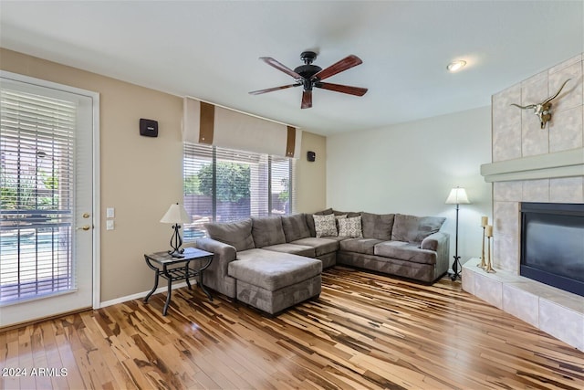 living room featuring wood-type flooring, plenty of natural light, ceiling fan, and a tiled fireplace