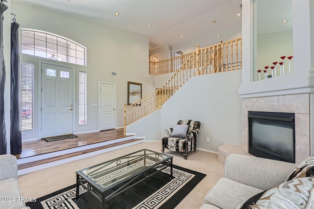 living room featuring a fireplace, a towering ceiling, and carpet flooring