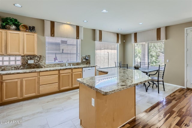 kitchen with a kitchen island, light brown cabinets, white dishwasher, and backsplash