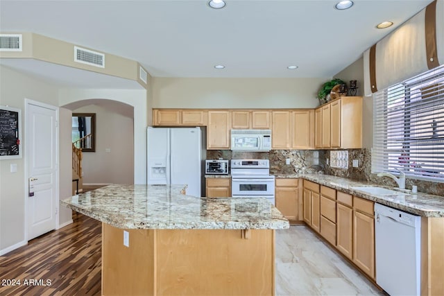 kitchen with a center island, tasteful backsplash, white appliances, and sink