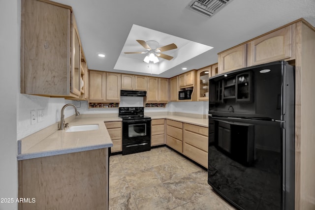 kitchen with black appliances, light brown cabinets, sink, and a tray ceiling