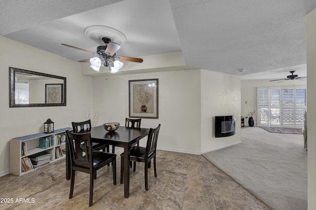 carpeted dining space with heating unit, a multi sided fireplace, ceiling fan, and a textured ceiling