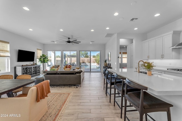 living room with ceiling fan, sink, and light wood-type flooring