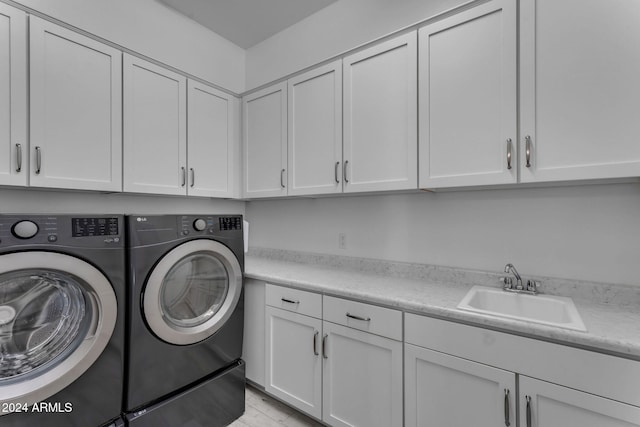 laundry room featuring washing machine and clothes dryer, sink, and cabinets