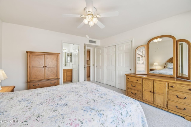 bedroom with ensuite bathroom, light carpet, visible vents, a ceiling fan, and a closet