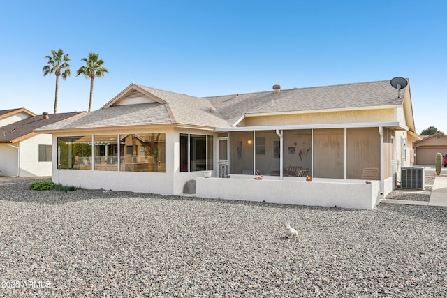 back of property with a shingled roof, a sunroom, and central AC unit