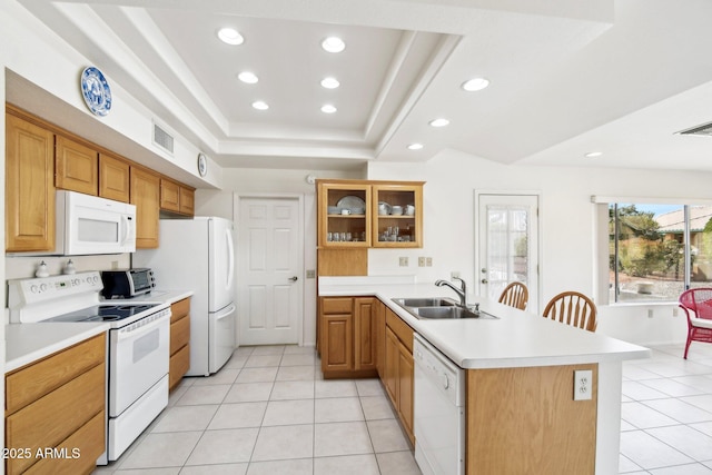 kitchen featuring white appliances, a raised ceiling, a peninsula, a sink, and light tile patterned flooring