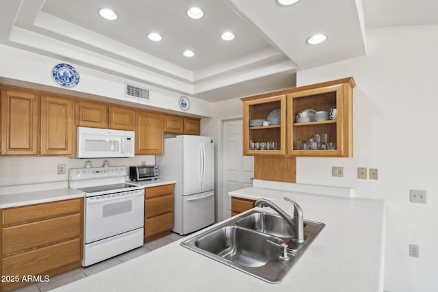 kitchen with white appliances, light tile patterned floors, a raised ceiling, glass insert cabinets, and a sink