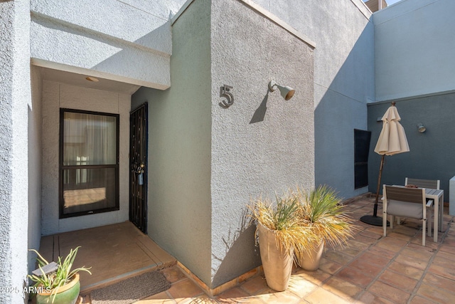 view of exterior entry featuring outdoor dining space, a patio area, and stucco siding