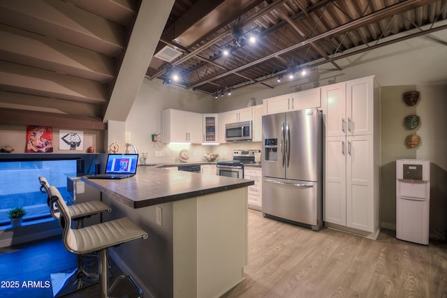 kitchen with stainless steel appliances, light wood-style floors, glass insert cabinets, white cabinetry, and a peninsula