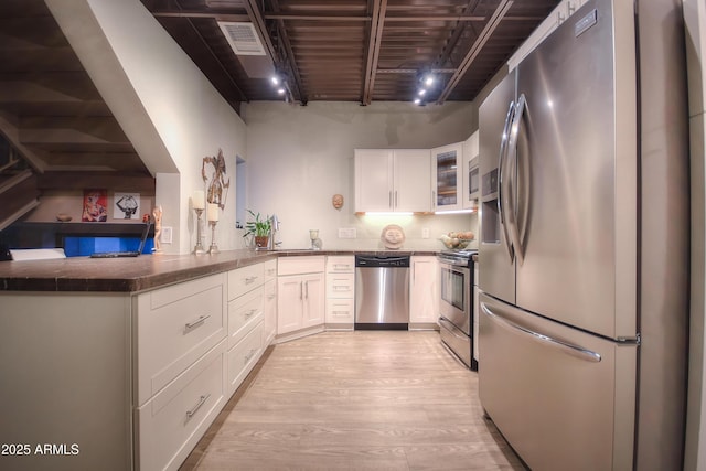 kitchen with light wood-type flooring, white cabinetry, stainless steel appliances, and glass insert cabinets