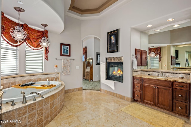 bathroom featuring a multi sided fireplace, tile patterned flooring, a bath, and vanity