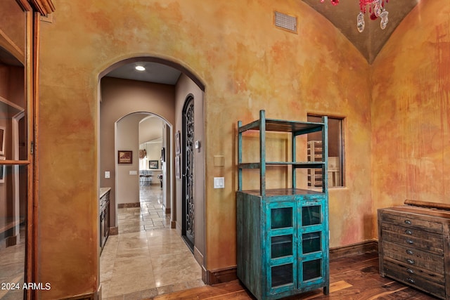 hall featuring high vaulted ceiling, visible vents, arched walkways, and baseboards