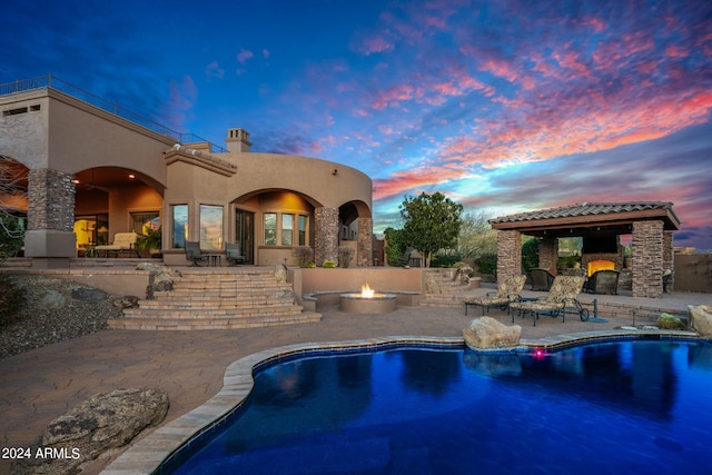 pool with exterior fireplace, a patio area, and a fire pit