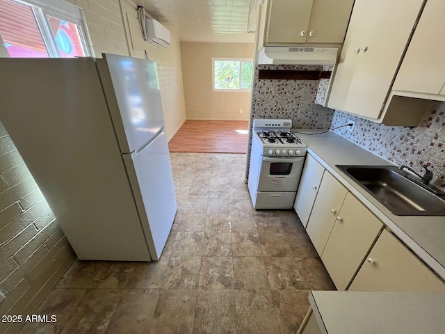 kitchen featuring tasteful backsplash, white appliances, a wall unit AC, sink, and range hood