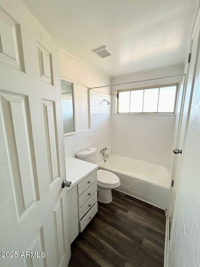 full bathroom featuring hardwood / wood-style floors, toilet, vanity, tile walls, and tiled shower / bath