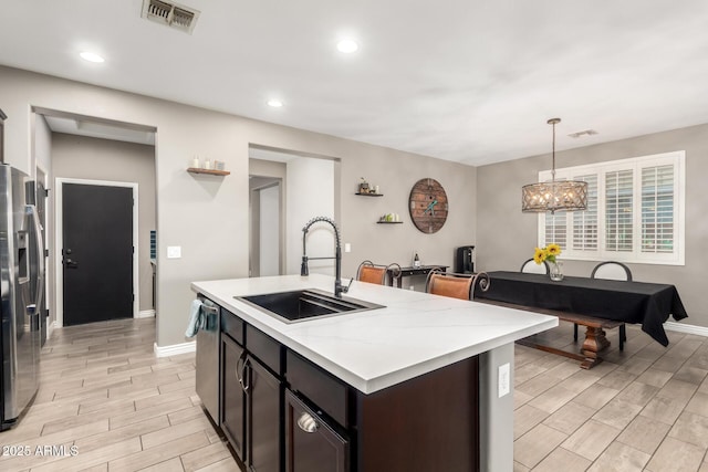 kitchen featuring sink, dark brown cabinetry, hanging light fixtures, stainless steel appliances, and a chandelier