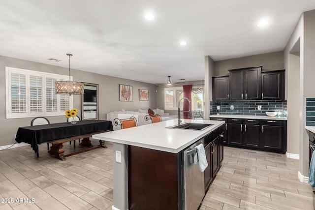 kitchen with pool table, sink, hanging light fixtures, stainless steel dishwasher, and a center island with sink