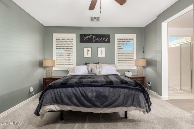 bedroom with ceiling fan, light colored carpet, and ensuite bath