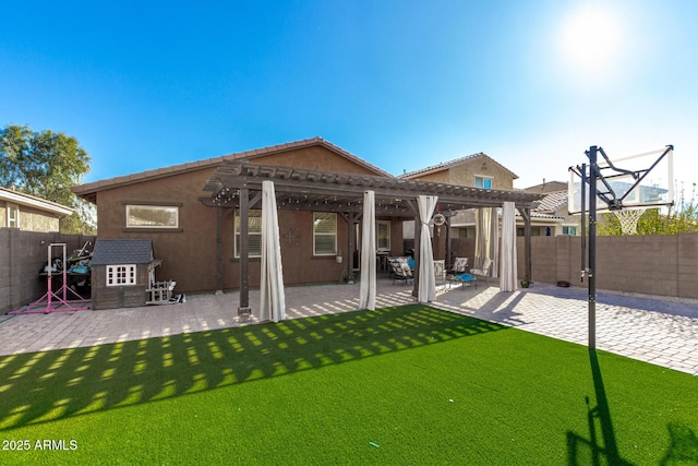 back of property with a pergola, a patio area, and a yard