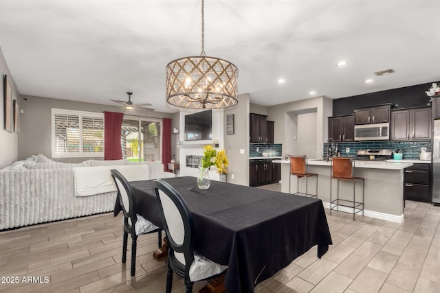 dining room with light wood-type flooring and ceiling fan with notable chandelier