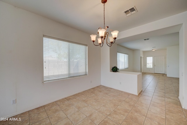 empty room with an inviting chandelier and light tile floors