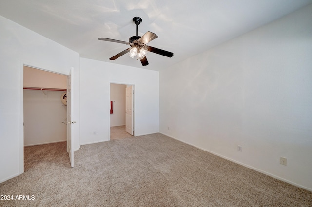 unfurnished bedroom with ceiling fan, a closet, light colored carpet, and a spacious closet