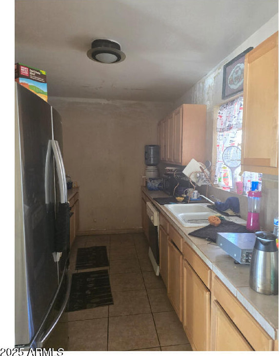 kitchen with tile patterned floors, light brown cabinetry, sink, stainless steel fridge, and dishwasher