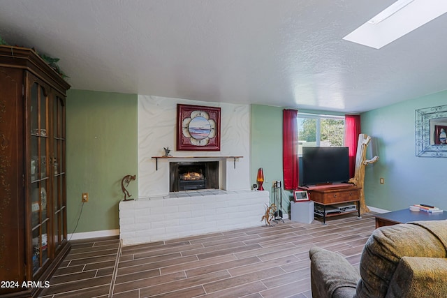 living room featuring a textured ceiling, a fireplace, and a skylight