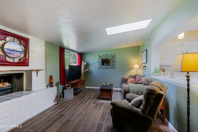 living room featuring dark hardwood / wood-style flooring, lofted ceiling with skylight, and a textured ceiling