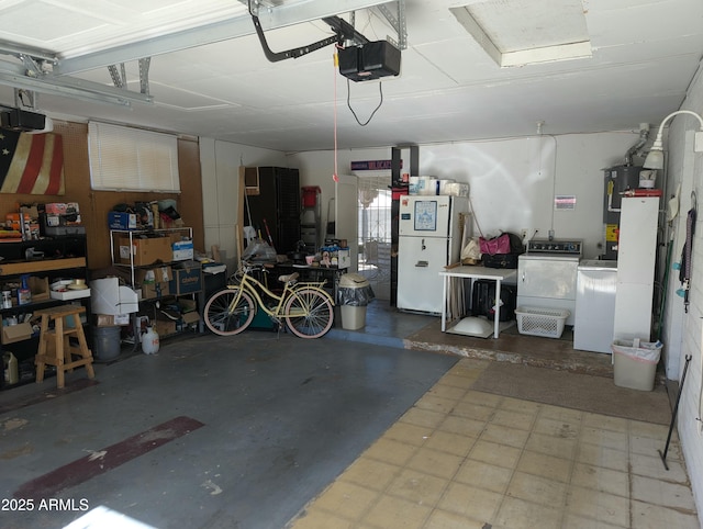 garage with washing machine and dryer, white fridge, a garage door opener, and water heater