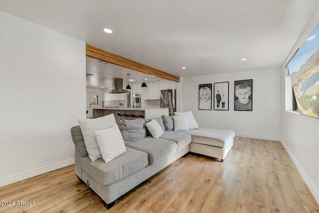 living room featuring beamed ceiling and light wood-type flooring