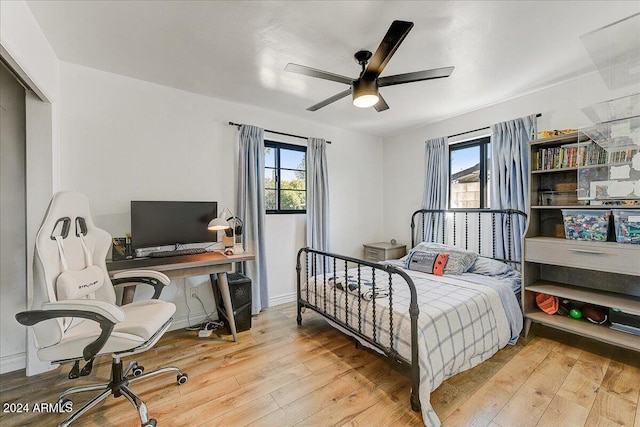 bedroom with a closet, light hardwood / wood-style floors, multiple windows, and ceiling fan