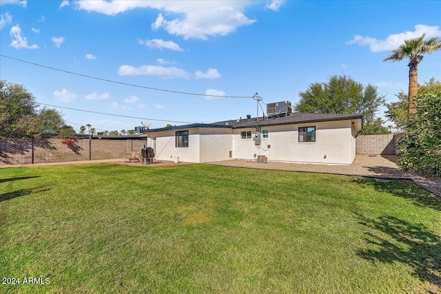 rear view of property with central AC unit and a lawn