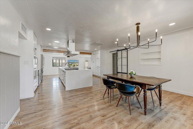 dining area with light hardwood / wood-style flooring, a textured ceiling, a barn door, and sink