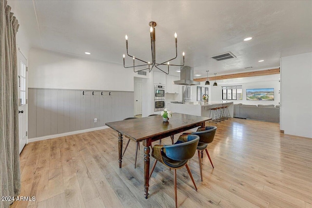 dining space with a notable chandelier and light hardwood / wood-style floors