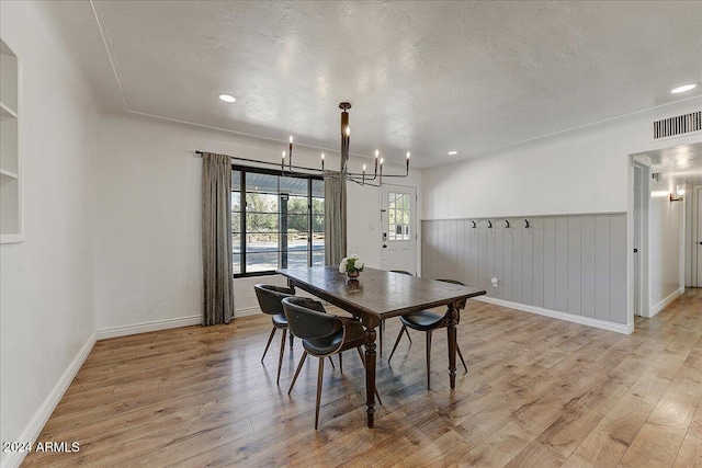 dining area featuring a chandelier, light hardwood / wood-style flooring, and a textured ceiling